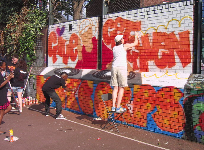 Volunteers creating graffiti mural at Orange Rockcorp workshop