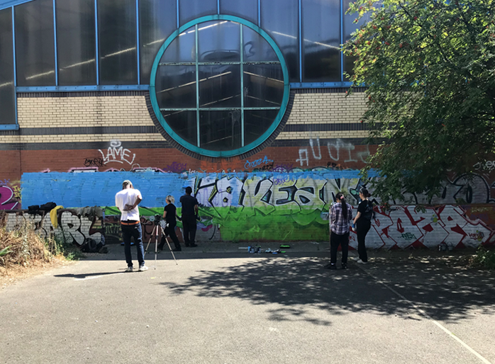 Volunteers spray painting community mural at Westway Sports Centre